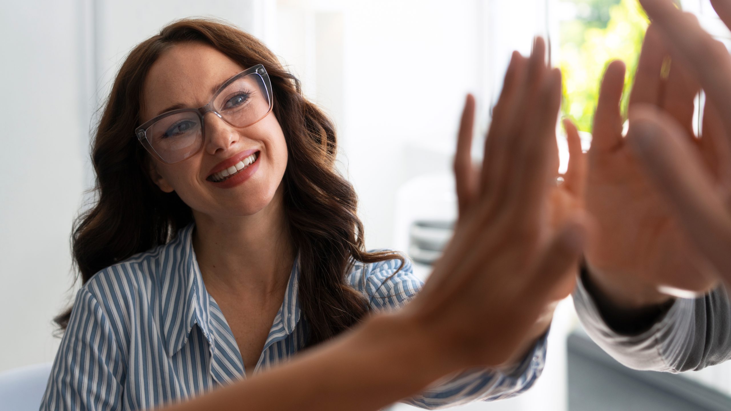 Urban Sports Club impulsa una nueva forma de vivir el bienestar corporativo en Redexis Una mujer junto a compañeros chochando manos en alto